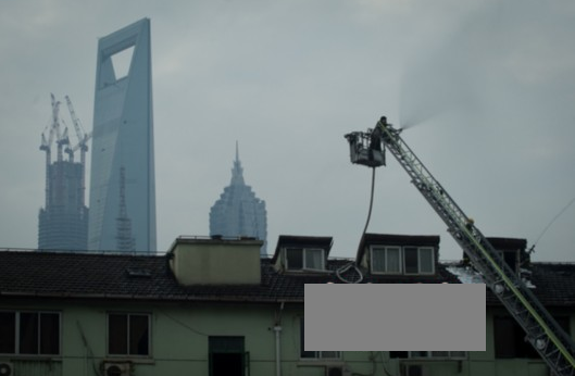 昨日,崂山新村,消防员通过云梯在屋顶进行灭火。