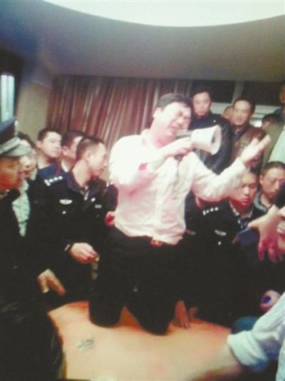 4月19日,泰州市滨江工业园区管委会招待中心,一男子跪在酒桌上喊话求饶。李根 摄
